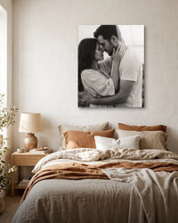 Black-and-white photo of a couple embracing on a frameless metal print above a sunlit bed